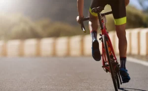 Parte inferiore del corpo di Domenico Pepe in sella alla sua bici da corsa rossa, ripreso posteriormente dalle anche in giù.